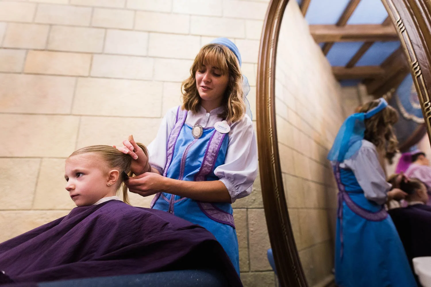 Fairy Godmother brushes little girl's hair at Bibbidi Bobbidi Boutique.