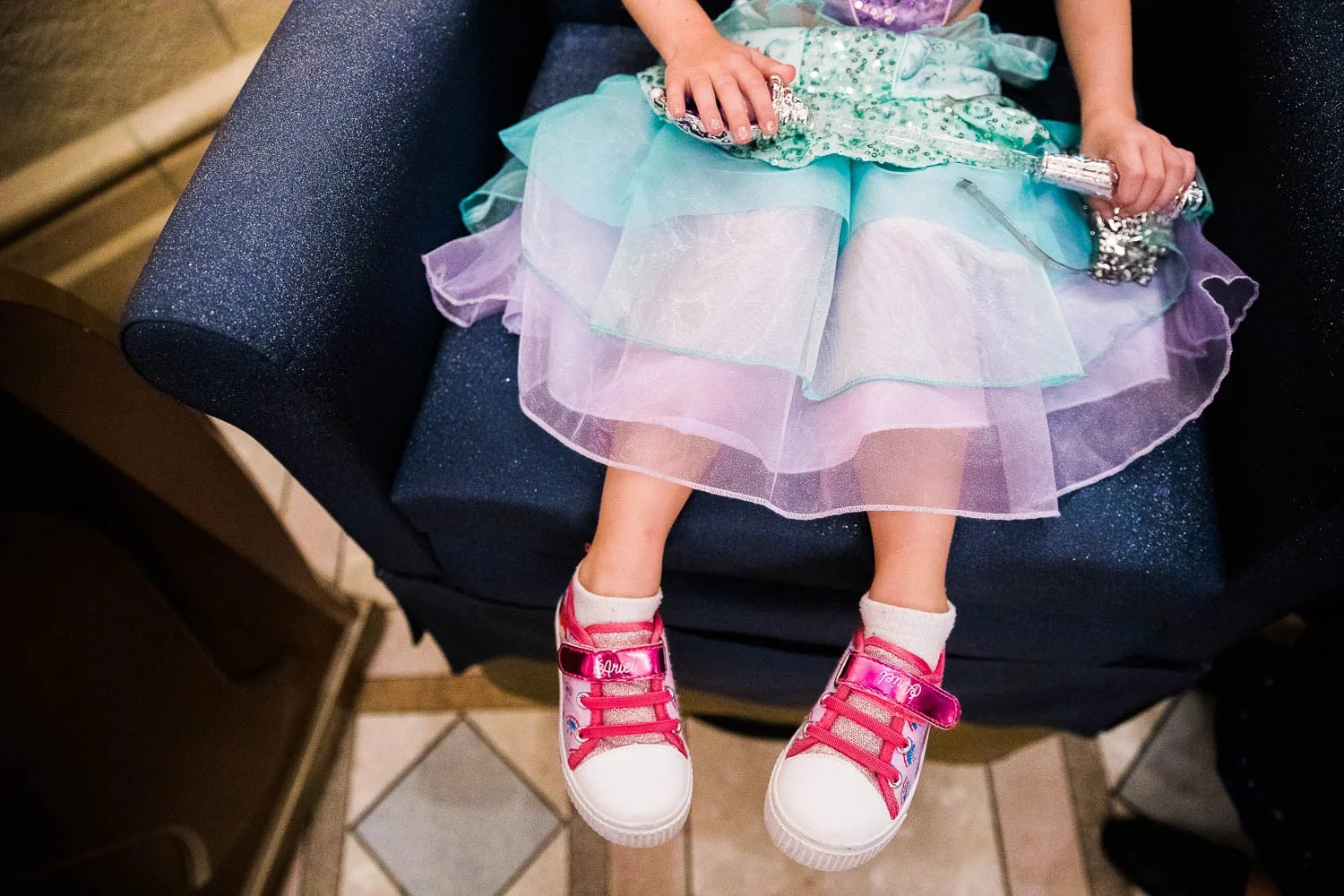 Up close detail of a little girl in bright pink sneakers and her Princess Ariel dress.