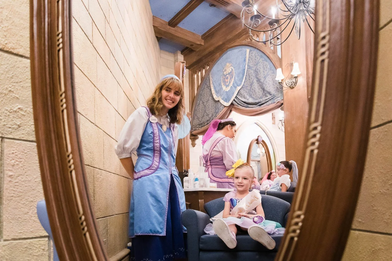 Fairy Godmother turns little girl around to see herself in the mirror at Bibbidi Bobbidi Boutique at Cinderella Castle.