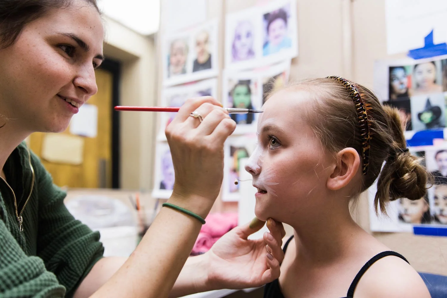 Volunteer paints faces backstage at the Wizard of Oz.