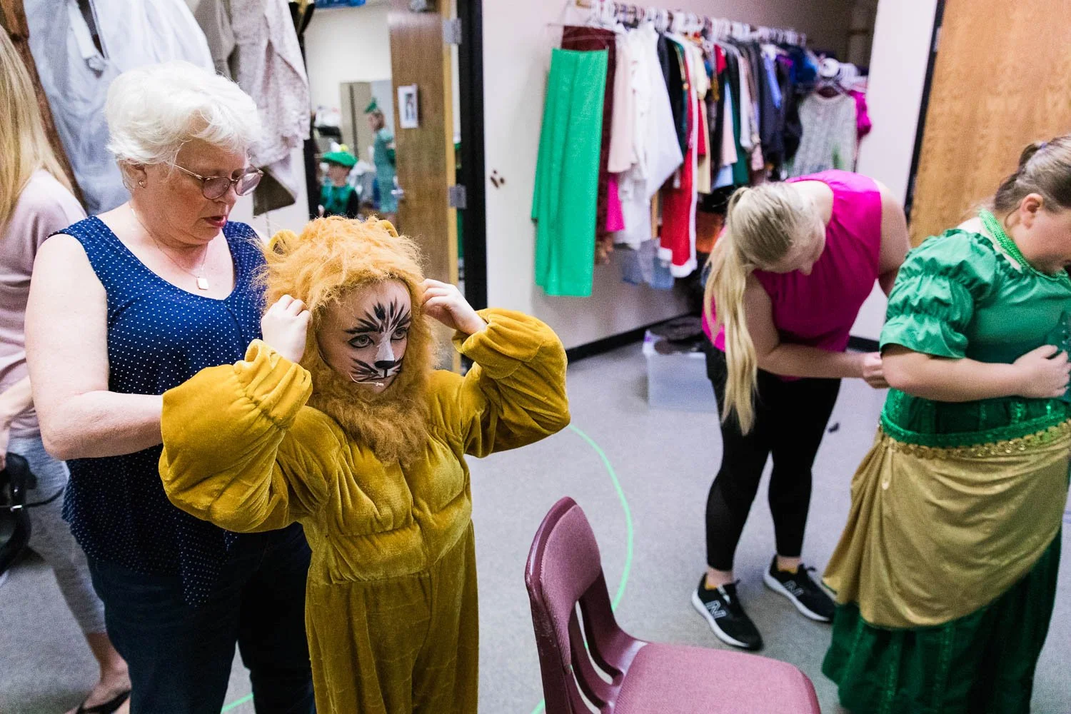 Volunteer helps the Lion get into costume for the Wizard of Oz stage production.