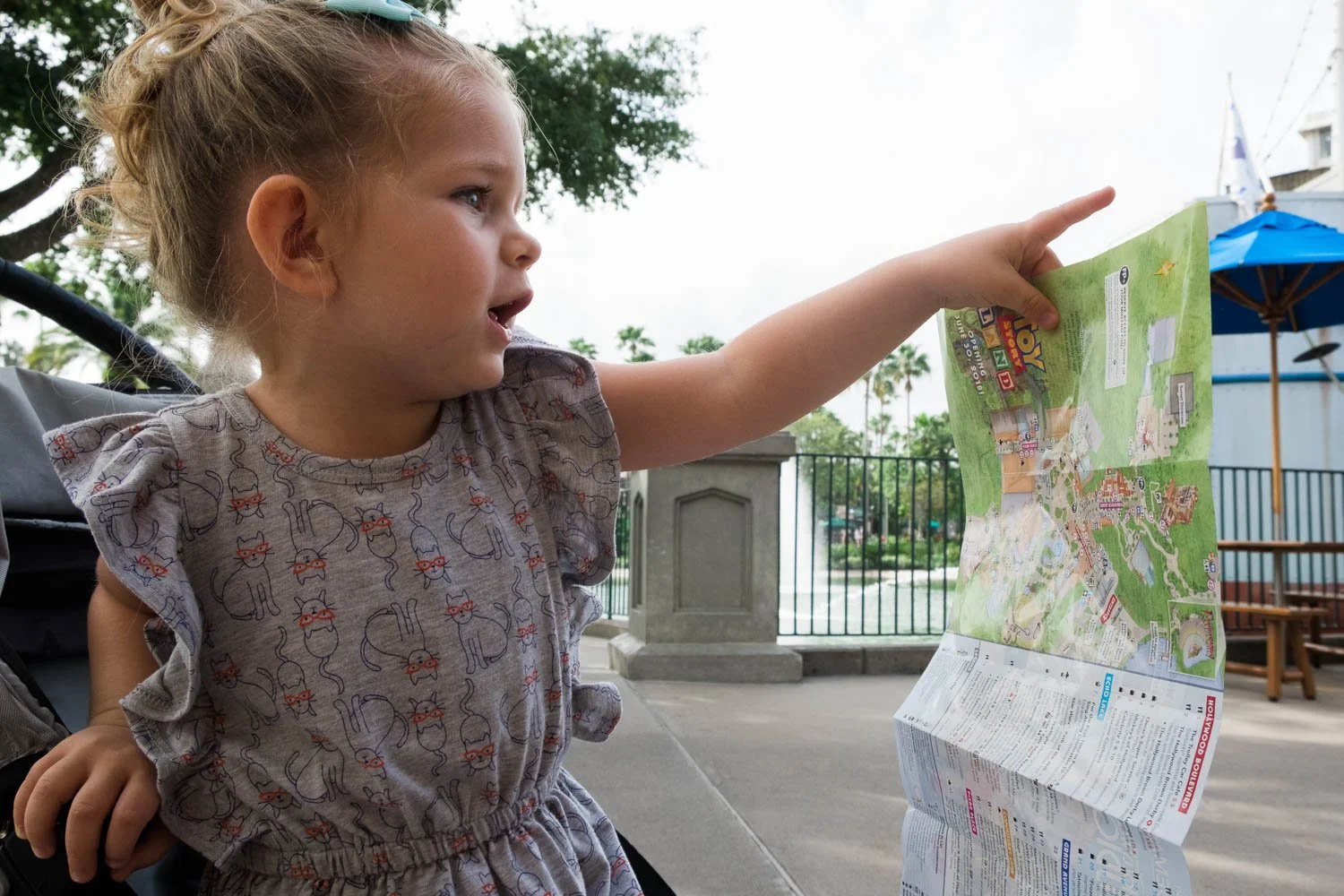 Toddler points out where to go after looking at Disney park map.