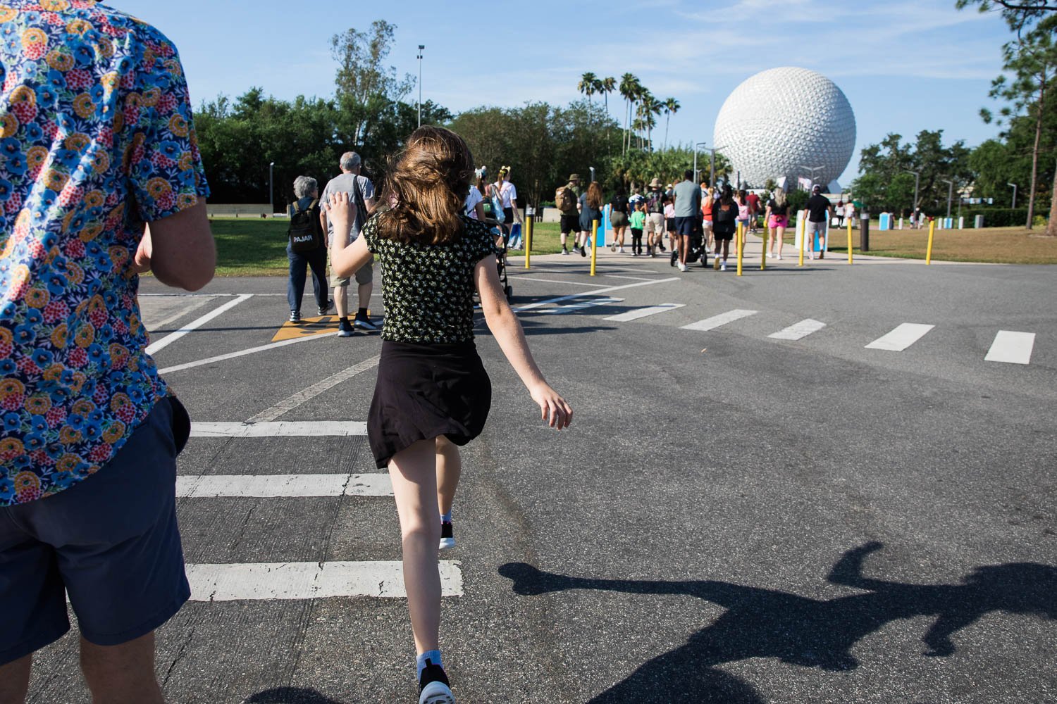 Young girl skips through Epcot parking lot towards Spaceship Earth.