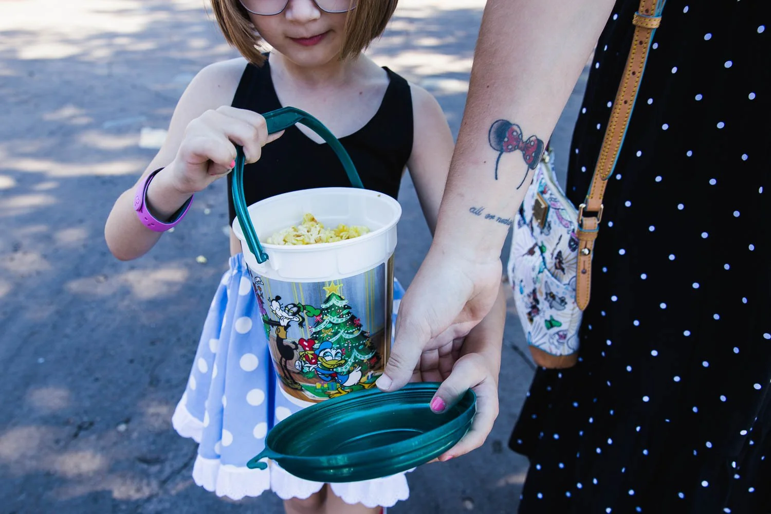 Mom and daughter walk with popcorn bucket at Magic Kingdom.