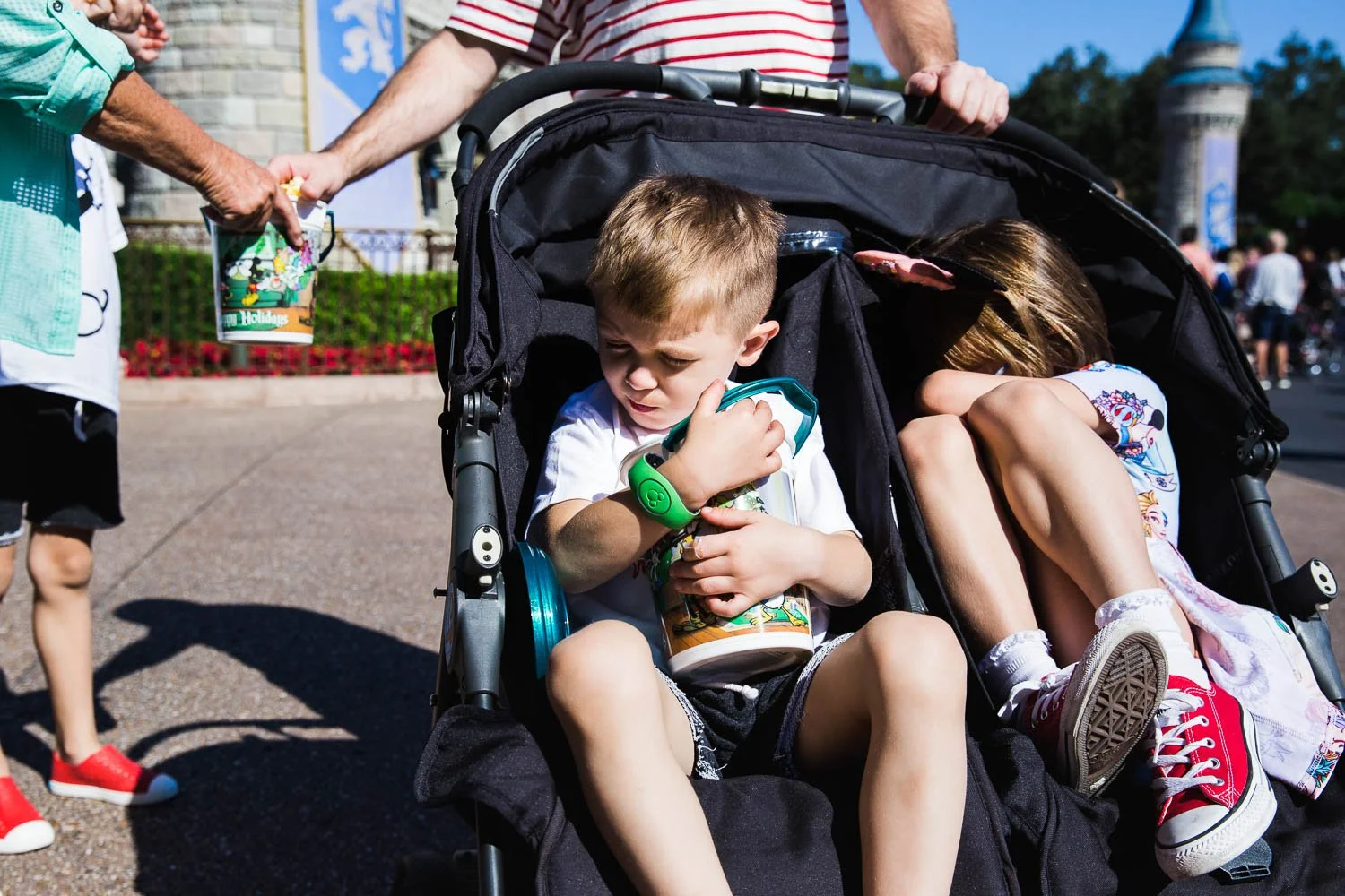 Kids in a stroller at the magic Kingdom fight over popcorn bucket.