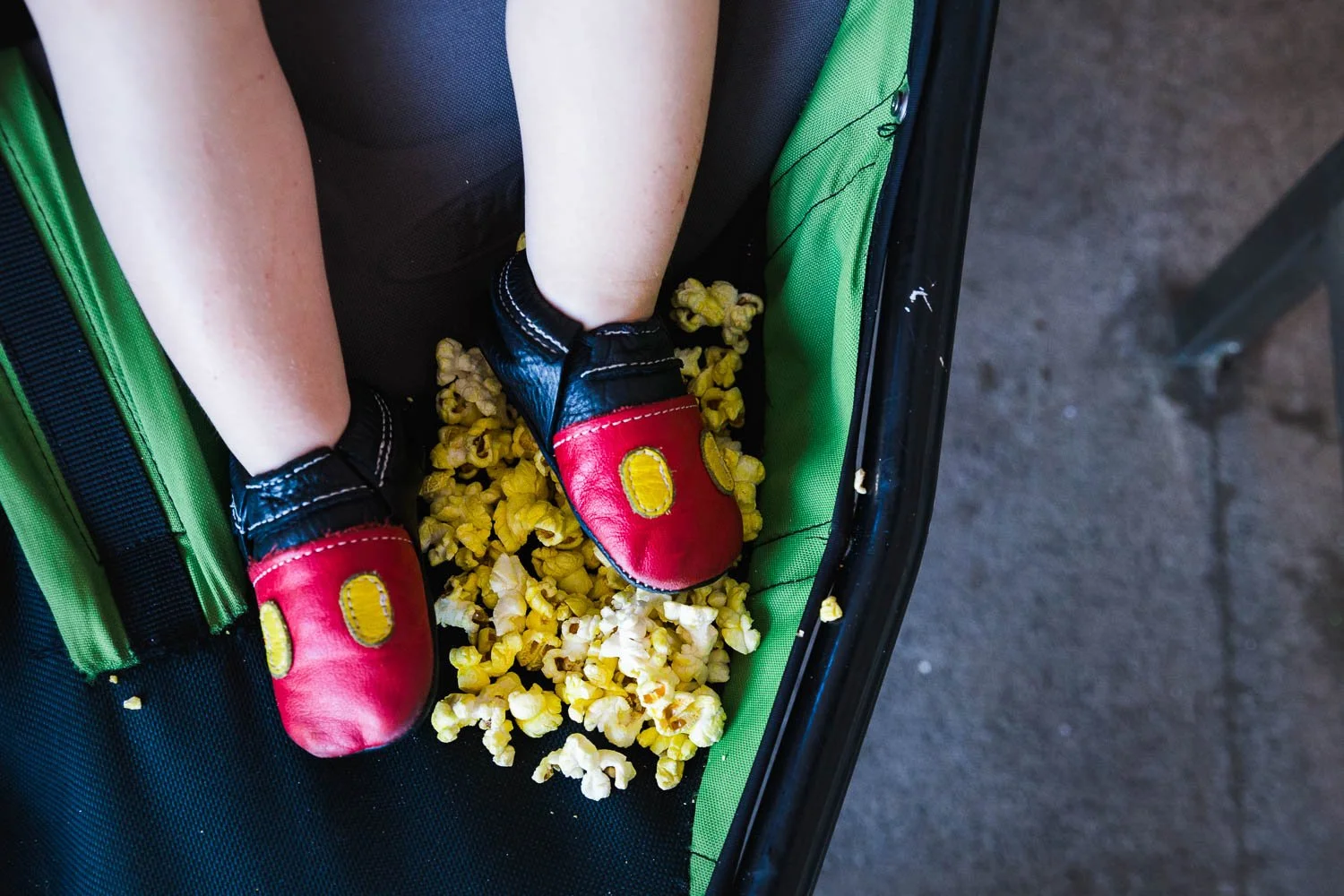 Up close toddler mickey shoes surrounded by popcorn.
