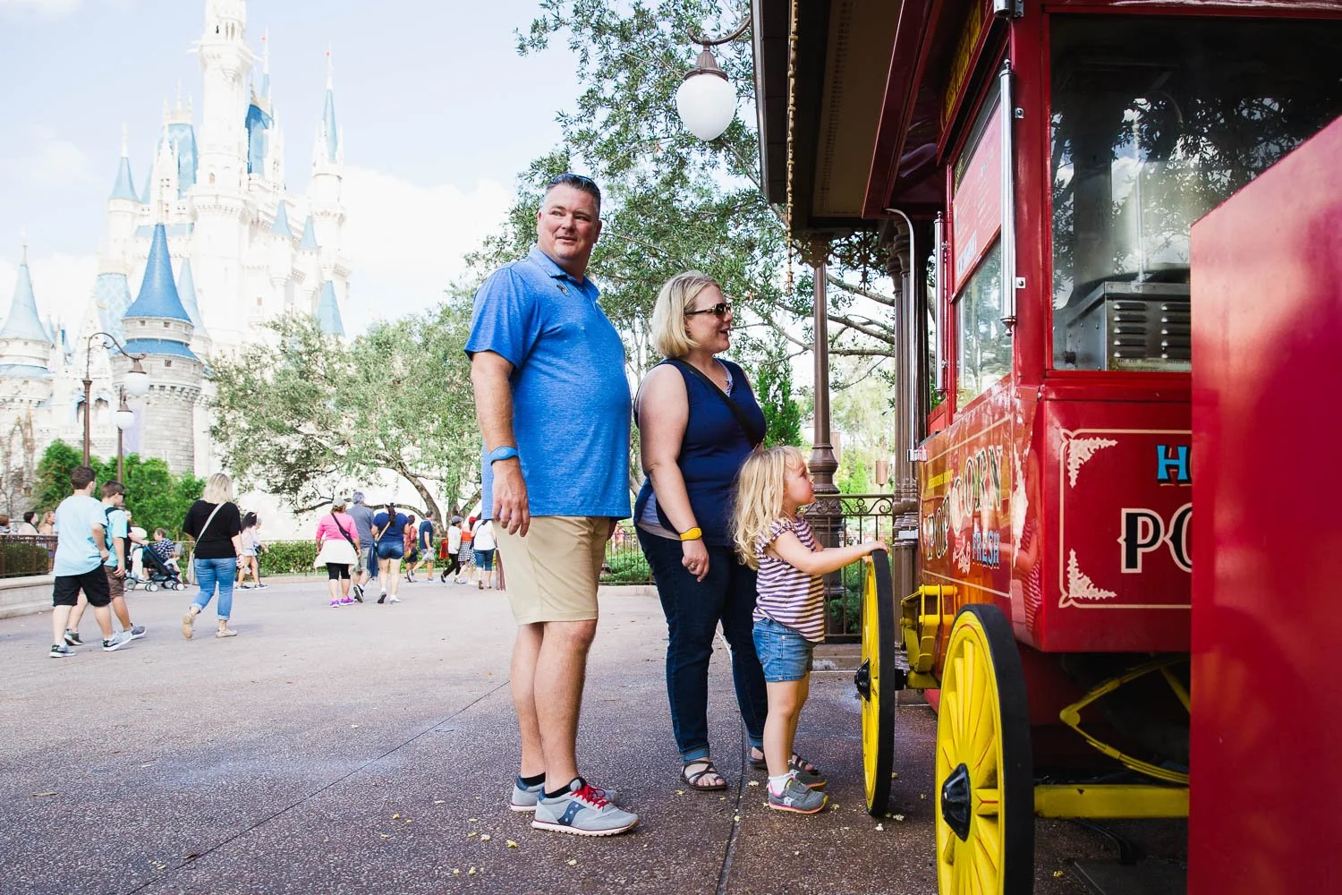Family stands at popcorn cart by Cinderella Castle.