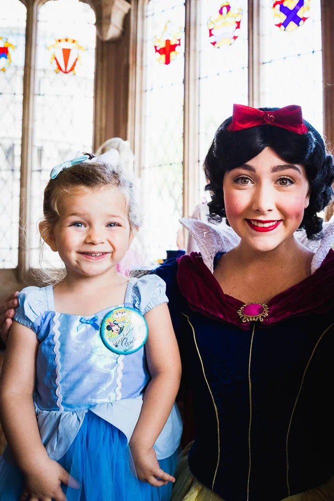 Three year old and Snow White make cheesy faces at the Magic Kingdom character breakfast.