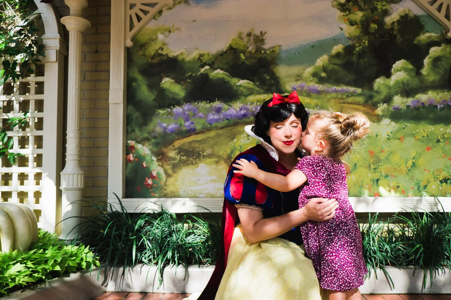 Toddler gives Snow White a kiss on the cheek at the Magic Kingdom.