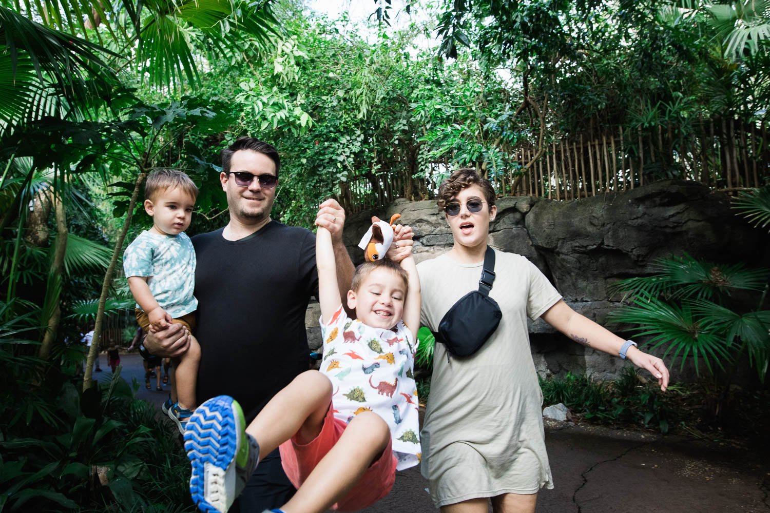 Parents swing child between them on a Gorilla Falls nature path at Animal Kingdom.