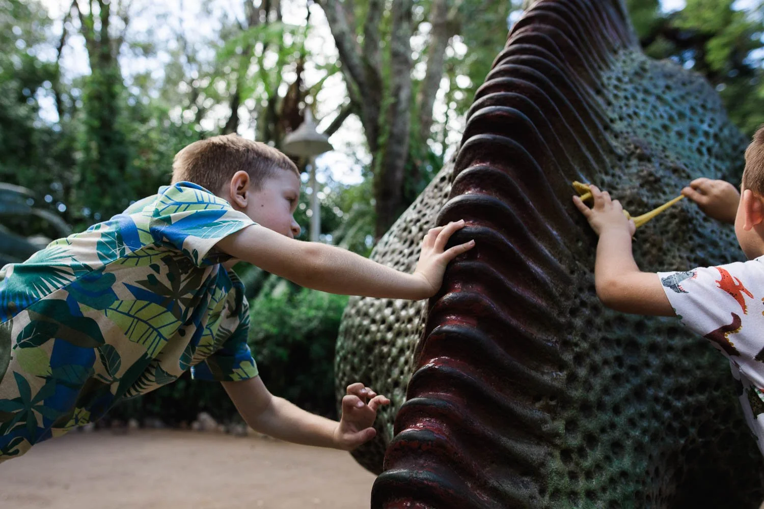 Boys play on dinosaur statue at the Animal Kingdom.