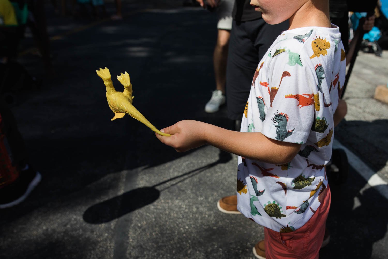 Boy plays with stretchy dinosaur while he waits to ride Triceratops Spin at the Animal Kingdom.