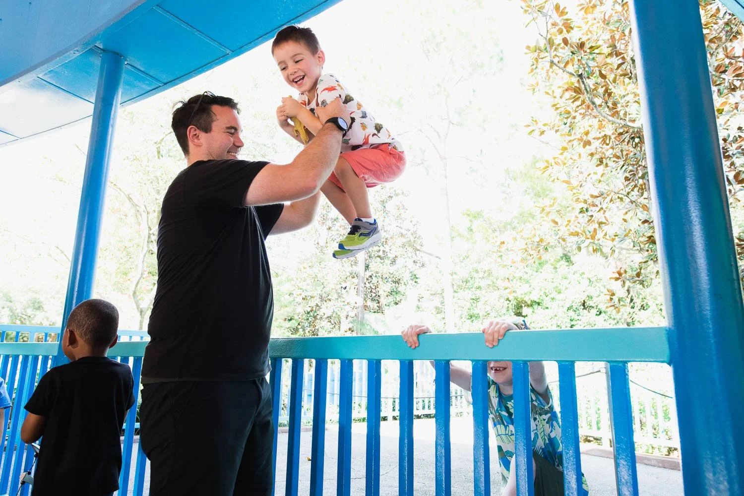 Father lifts boy high in the air in the queue for Triceratops Spin at Animal Kingdom.
