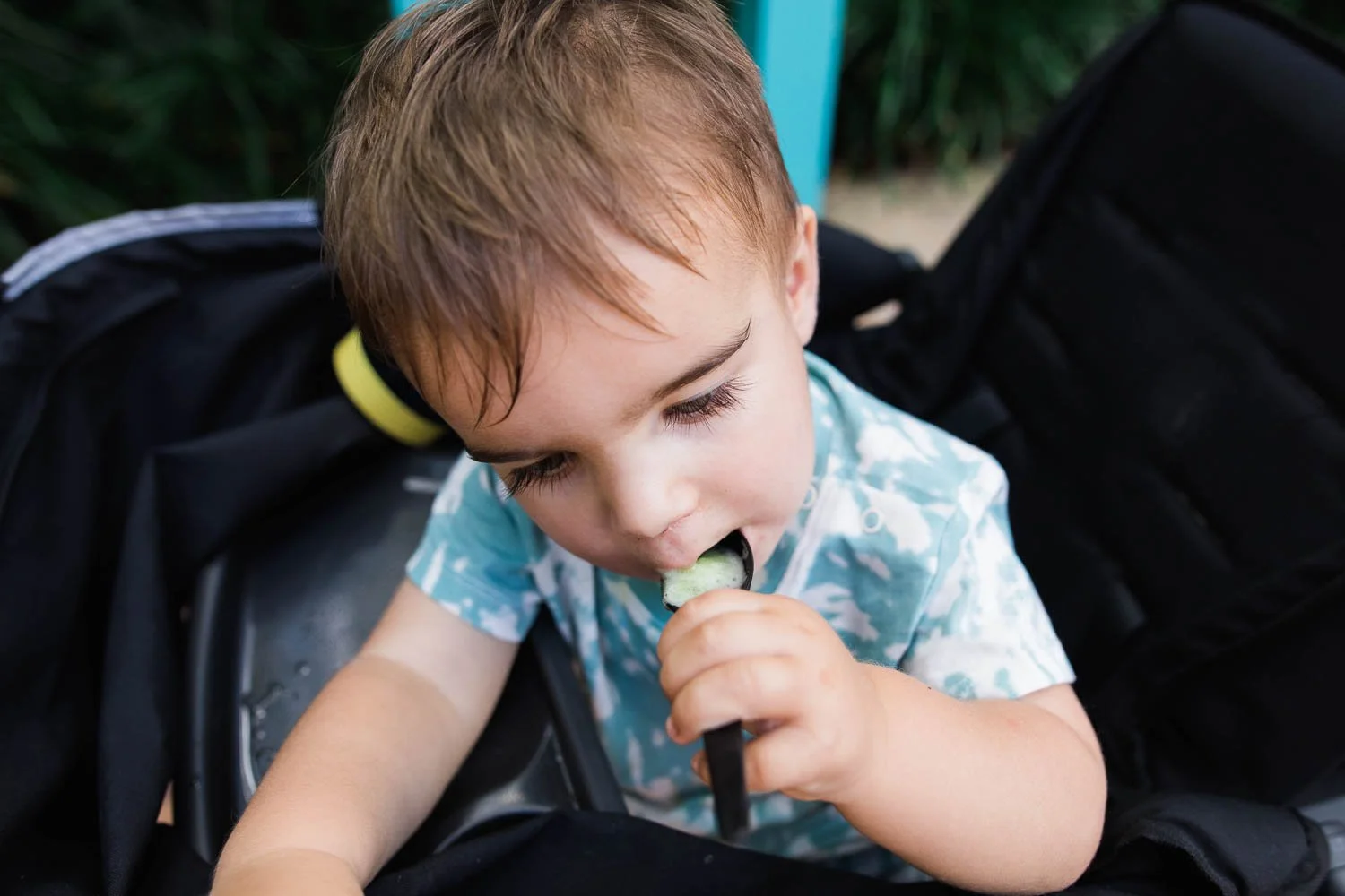 Toddler feeds himself a frozen lemonade in Dinoland USA.
