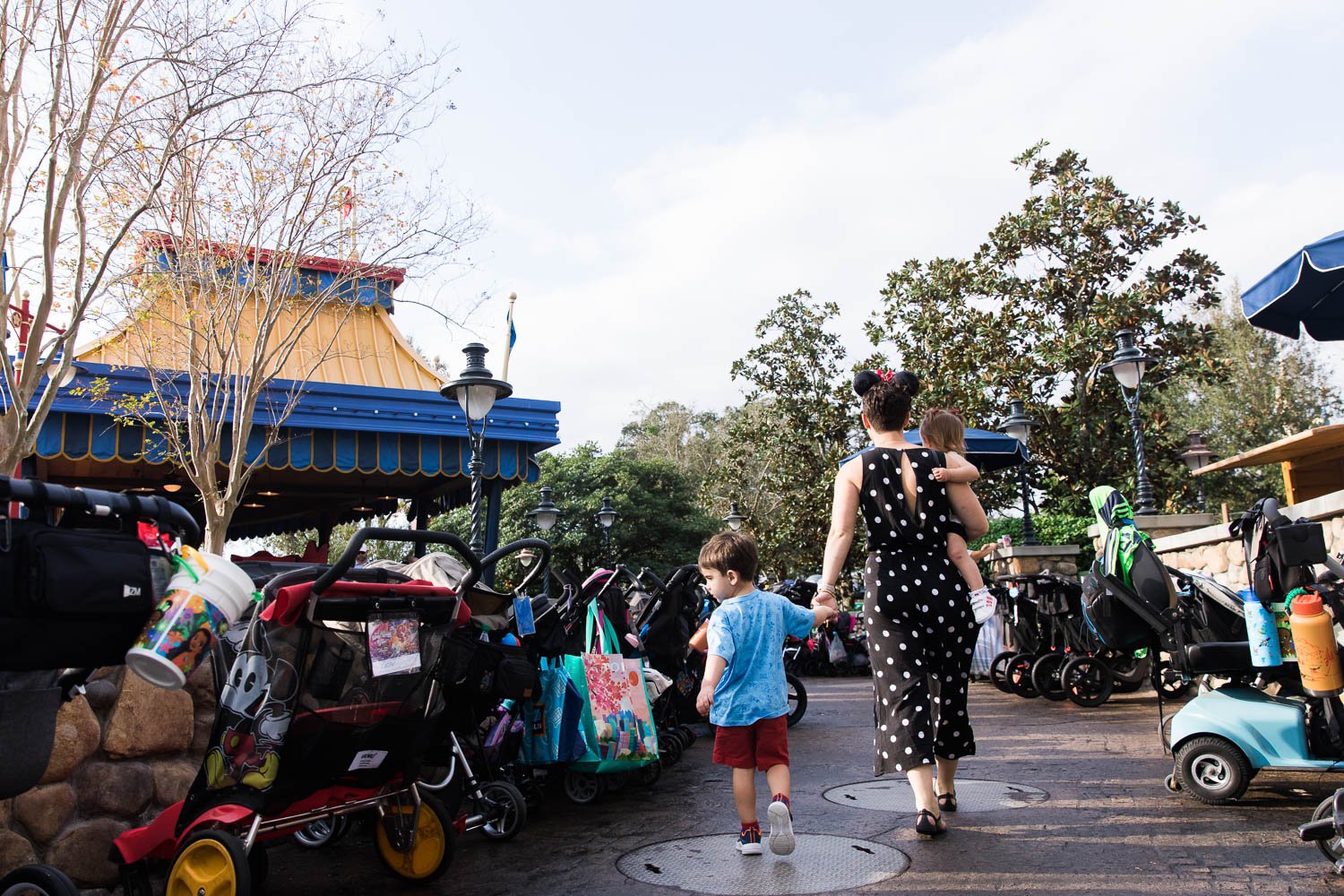 Mother holds hands with her son as they search for stroller outside Dumbo attraction at Disney World.