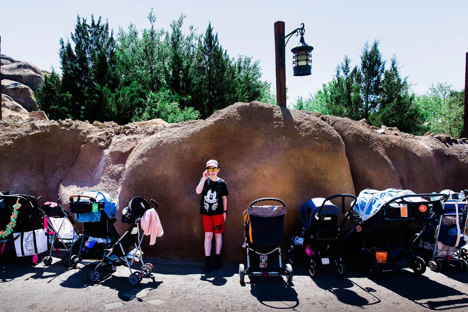 Tween boy stands amidst a line of strollers at the Magic Kingdom.