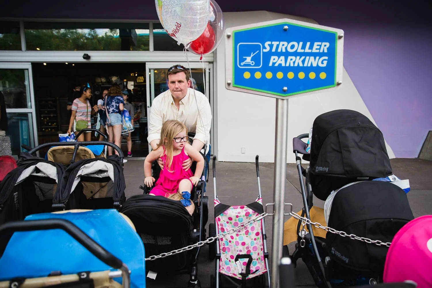 Father lifts daughter out of stroller in Tomorrowland at the Magic Kingdom.