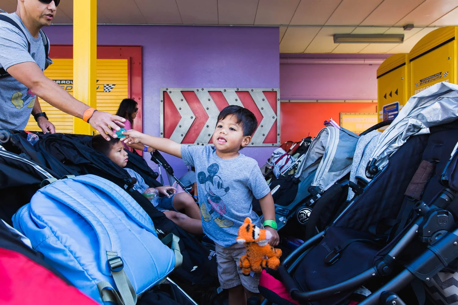 Son hands his pacifier to his dad when he gets out of his stroller at the Magic Kingdom.