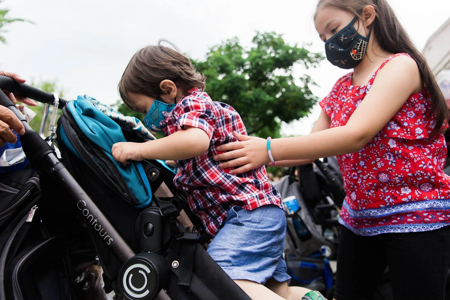 Big sister helps her little brother get back in the stroller at Walt Disney World.