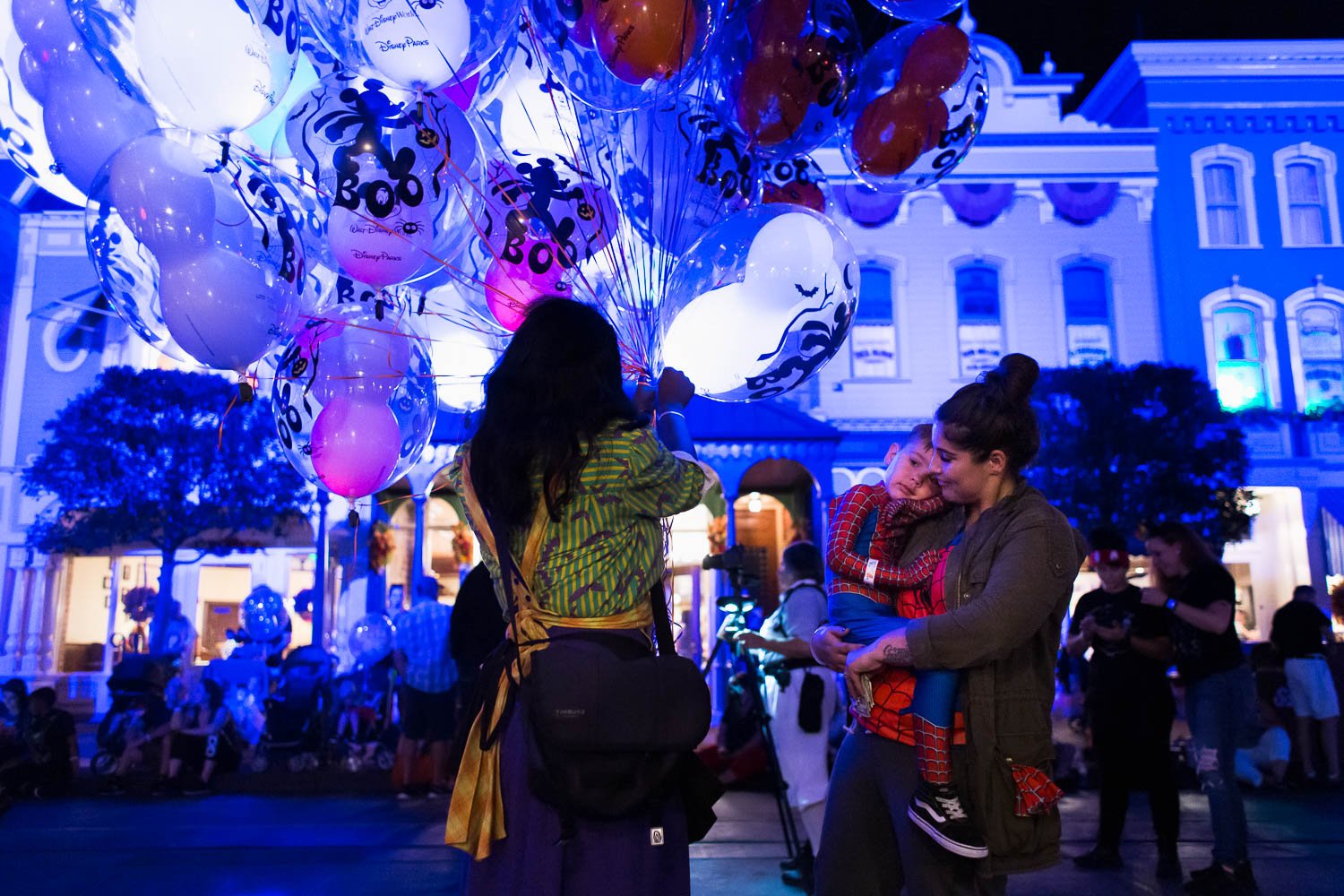 Mother holds tired son on Main Street during nighttime event at the Magic Kingdom.