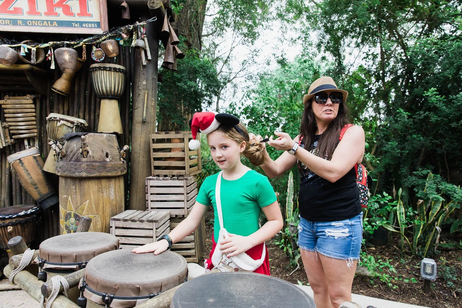 Mother fixes daughter's hair while she plays on the African drums at the Animal Kingdom.