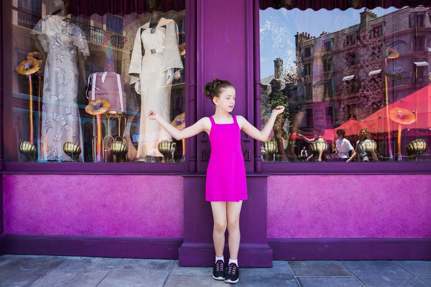Little girl stands in front of shops in the Wizarding World of Paris.
