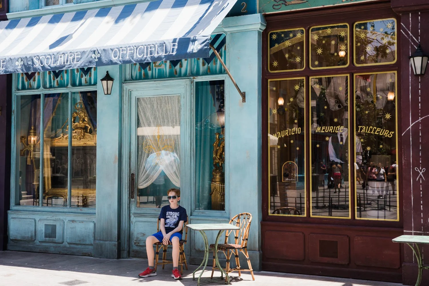 Boy finds small bit of shade to get out of heat in Wizarding World at Epic Universe.