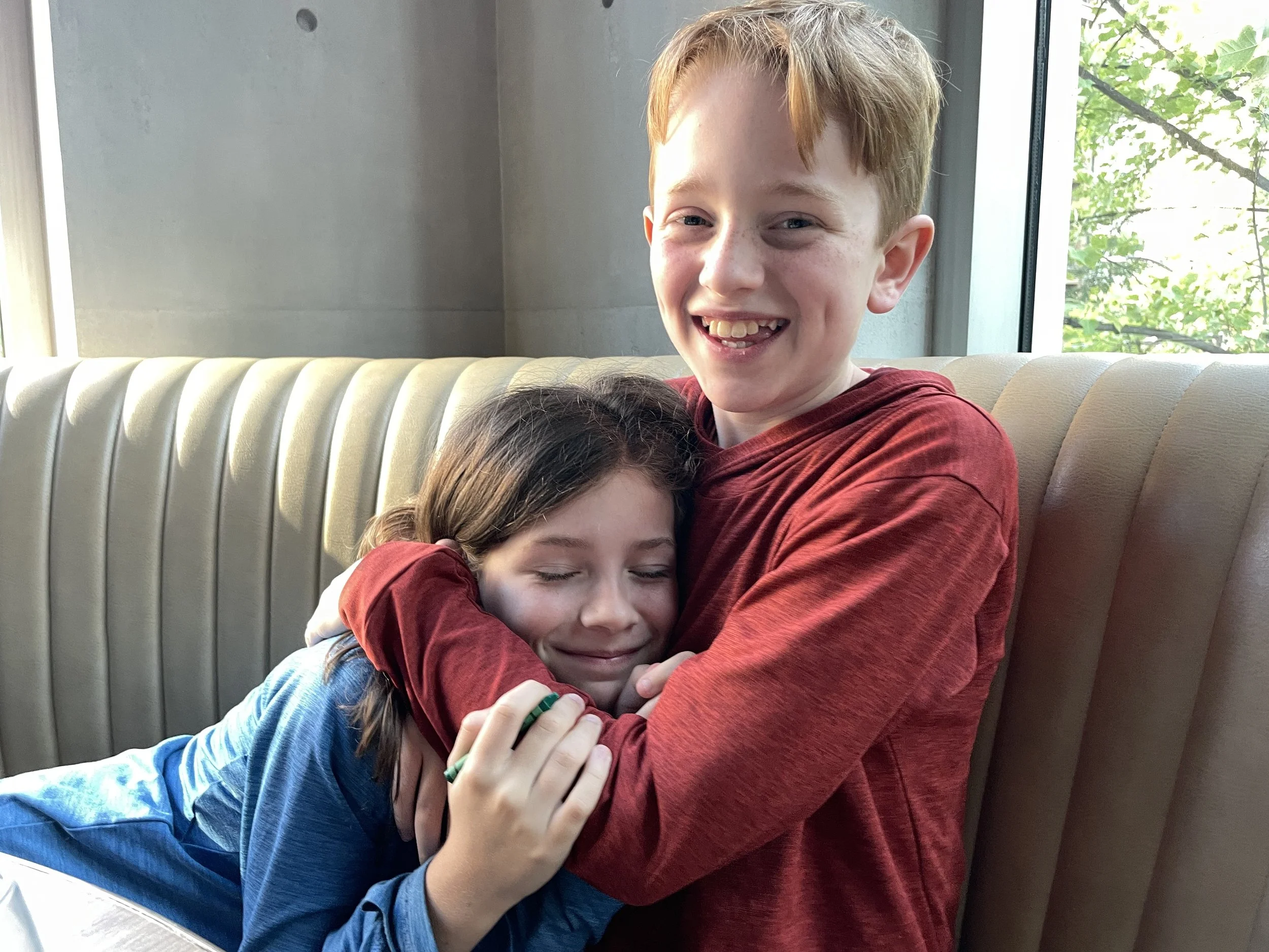 Siblings hug while waiting for their dinner at Hendricks Hilton Vancouver.