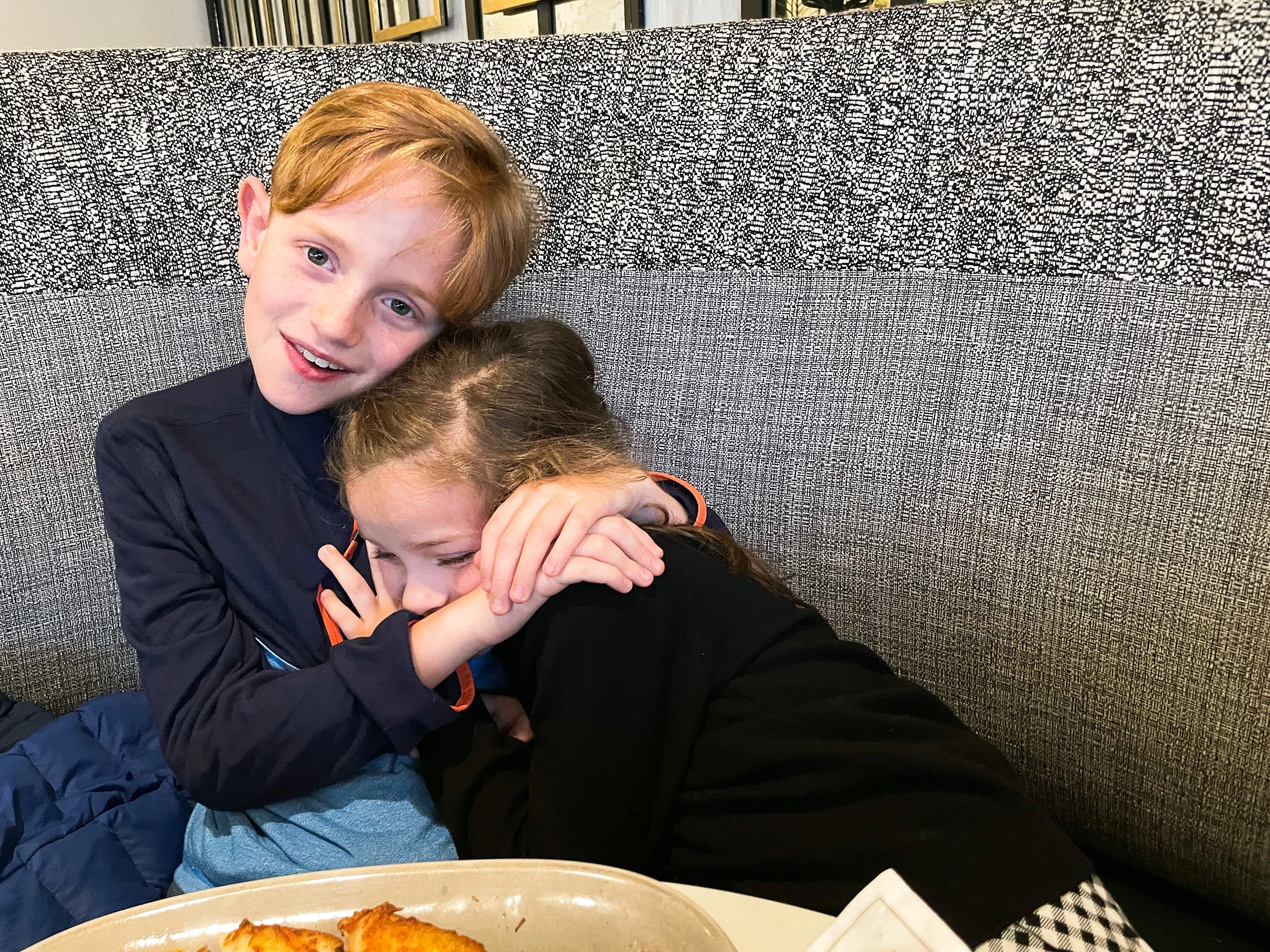 Siblings hug while waiting for their dinner at a bistro in Trocadero Paris.