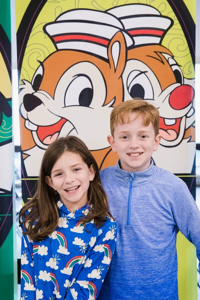 Kids pose in front of a Chip and Dale sign while waiting to board the Disney Wonder.
