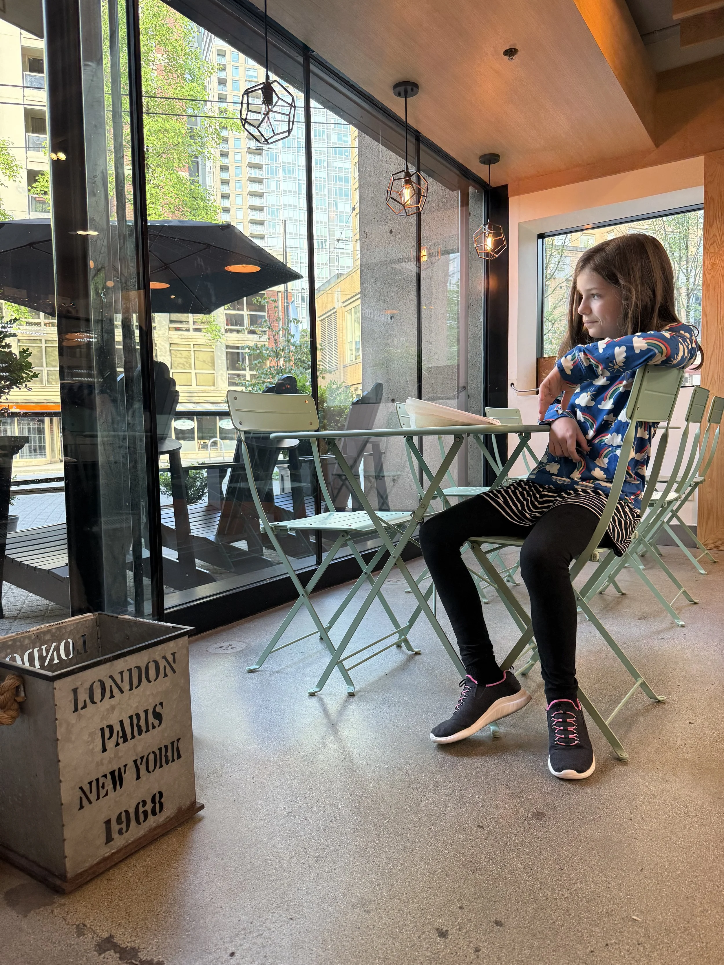 Pre-teen girl sits at an empty restaurant in Vancouver, BC.