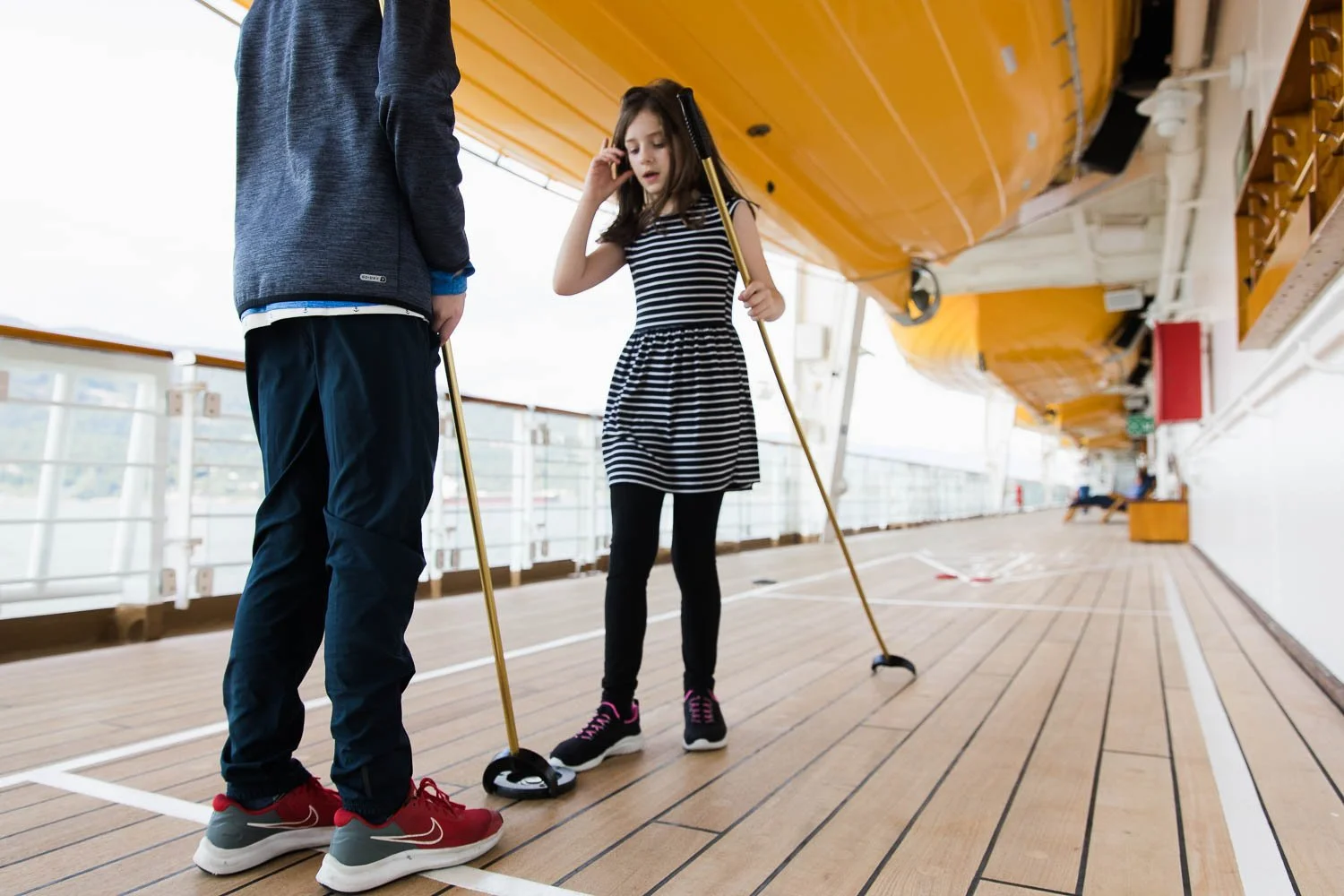 Siblings play shuffleboard on board the Disney Wonder.
