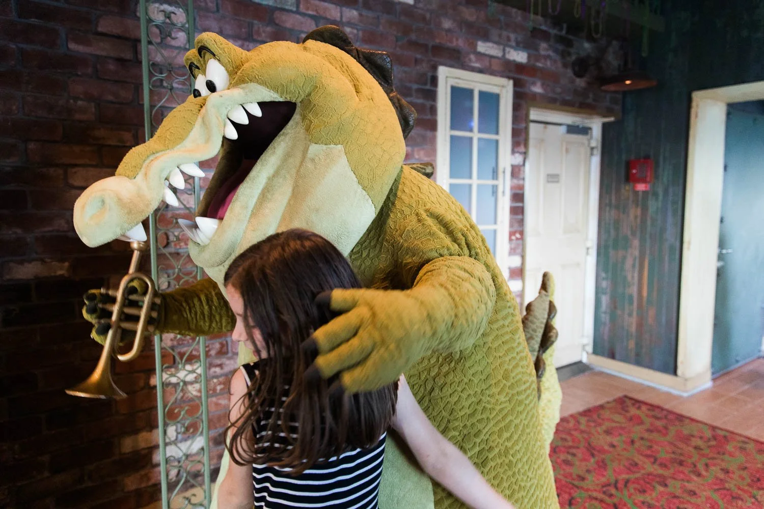 Little girl gives Louis, from the Princess and the Frog, a hug outside Tiana's Place.