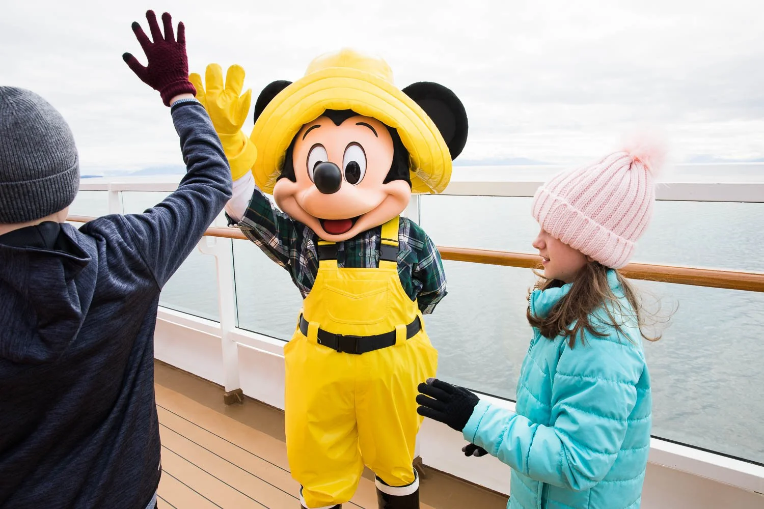 Tween boy high fives Mickey Mouse on a Disney cruise ship in Alaska.