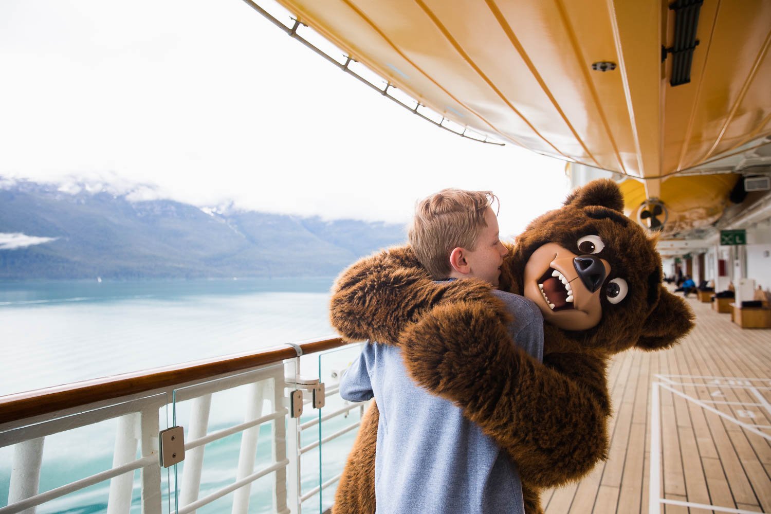 Teen boy hugs Koda on deck four of the Disney Wonder.