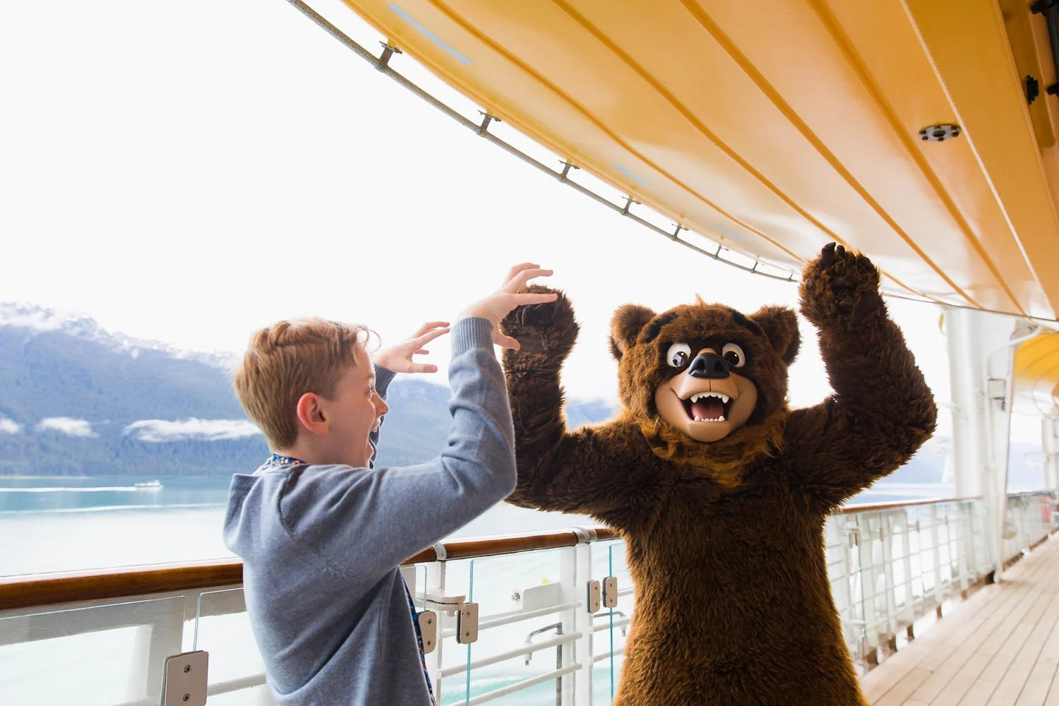 Tween boy does poses as a bear with Koda of Brother Bear on the Disney Wonder.