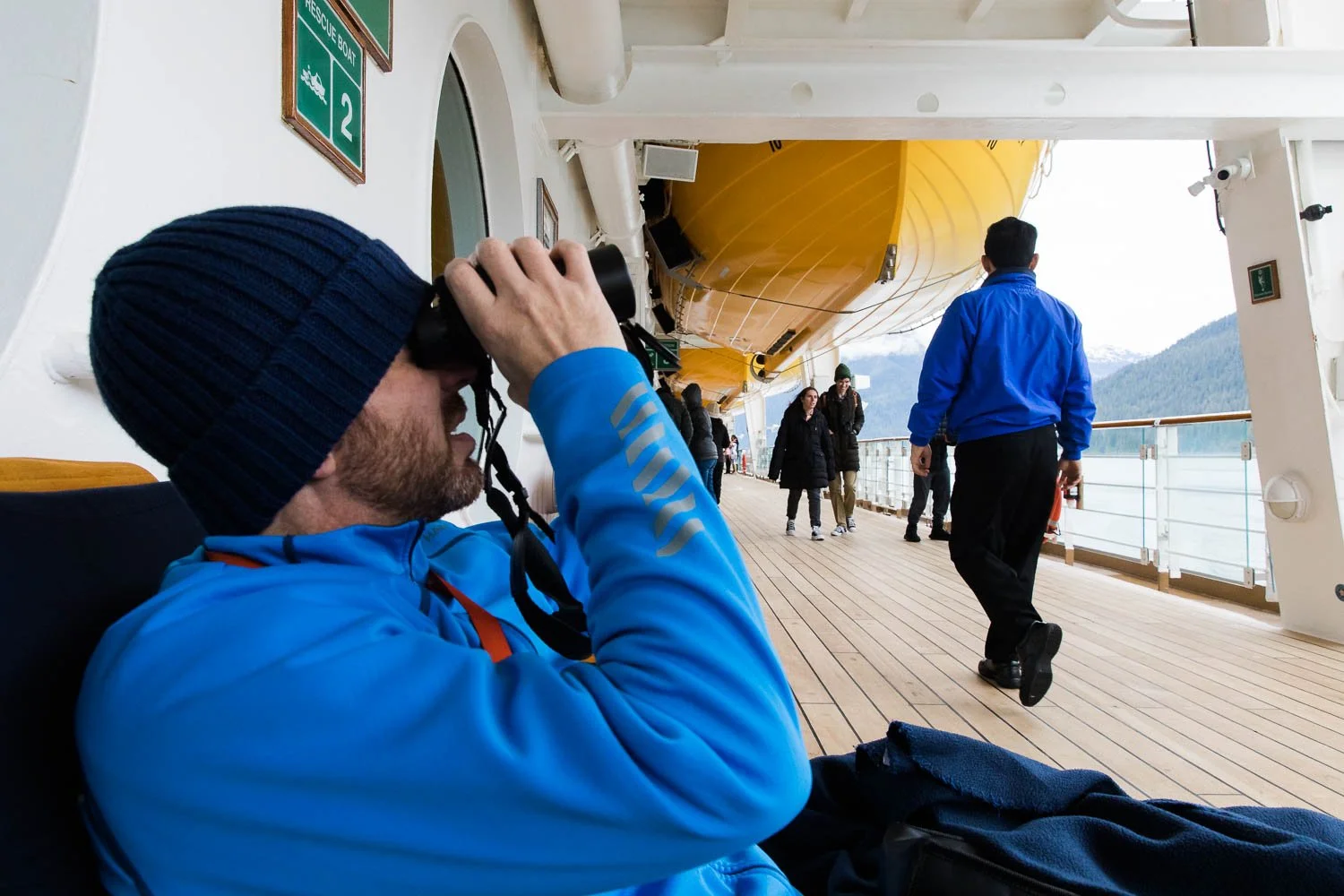 Man looks through binoculars at the wildlife in Alaska.