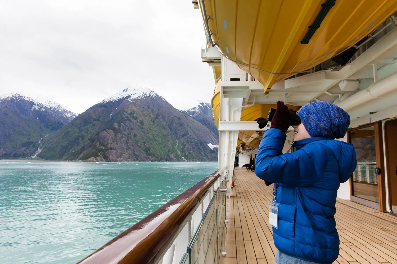 Boy uses binoculars to look for bald eagles and bears in Alaska.