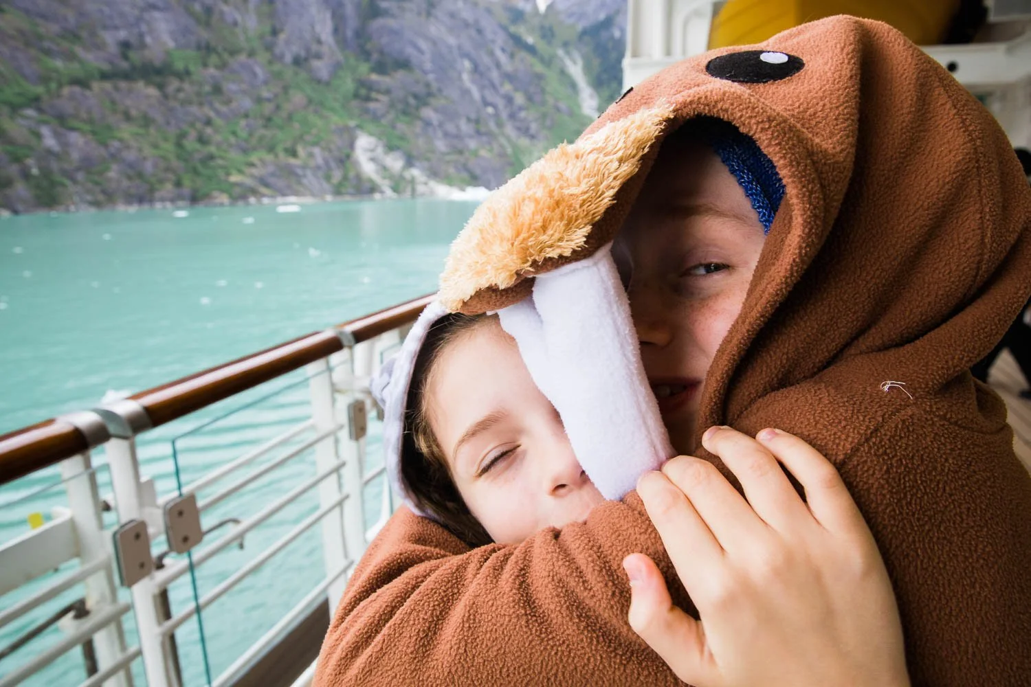 Brother and sister, dressed as walrus and snow leopard, hug in Alaska.