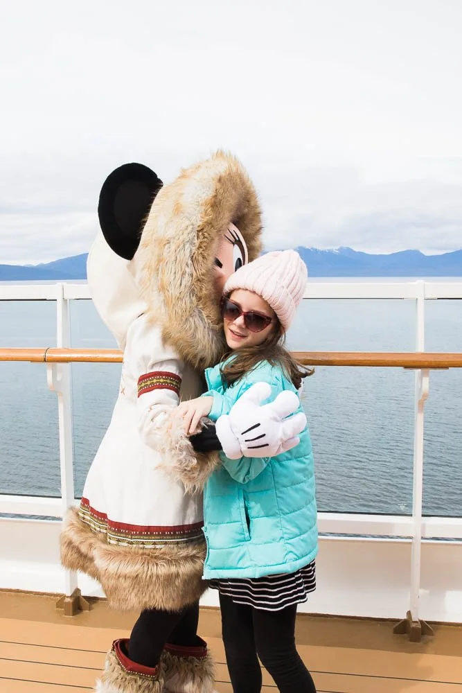 Young girl gives Minnie Mouse a hug onboard the Disney Wonder in Alaska.