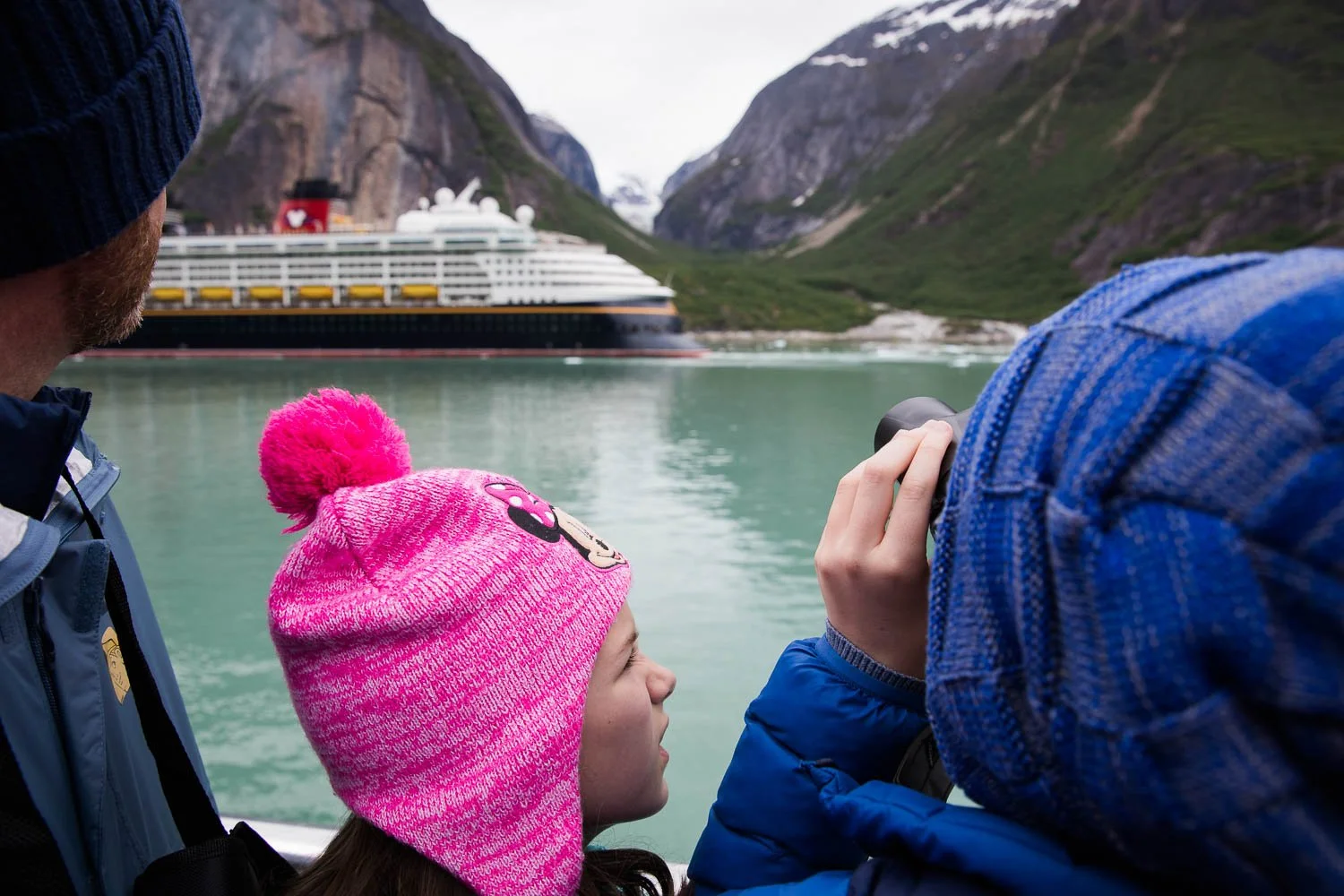 Family looks off at Disney Wonder in Alaskan Fjord.