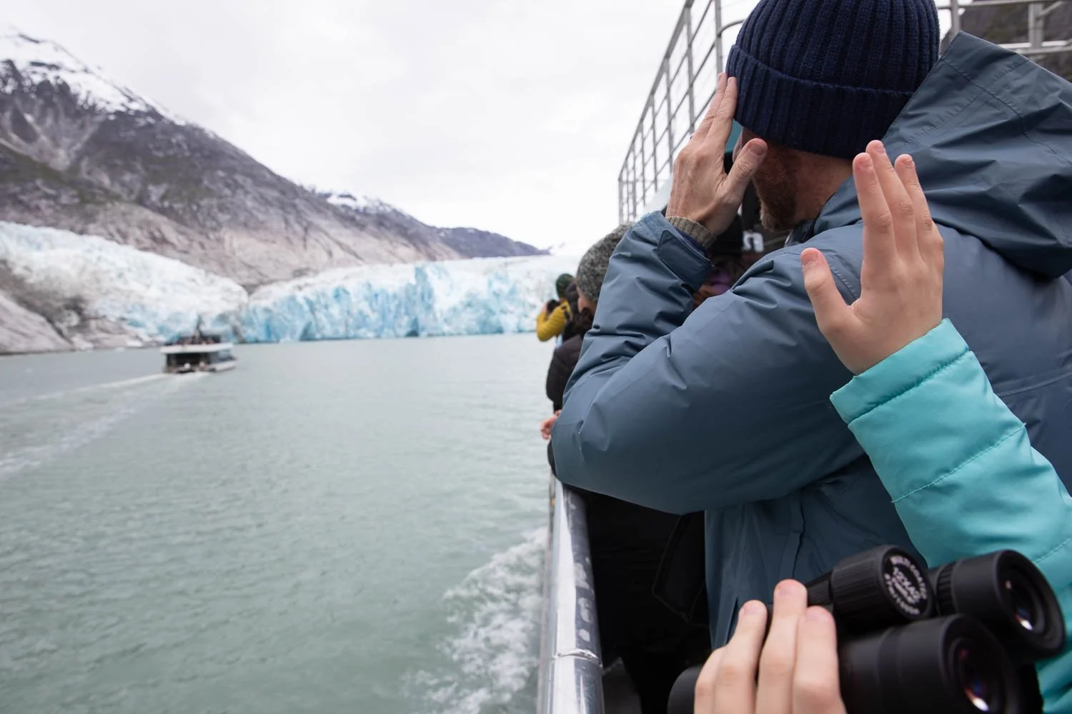 Girl waves at a boat in Alaska fjord.