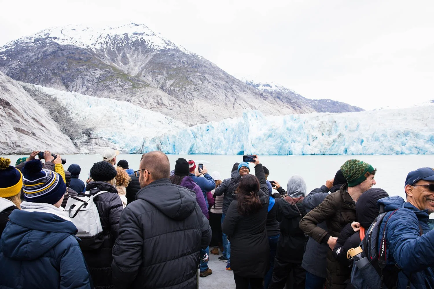 Tourists take photos of Dawes Glaciers from their boat excursion in Alaska.