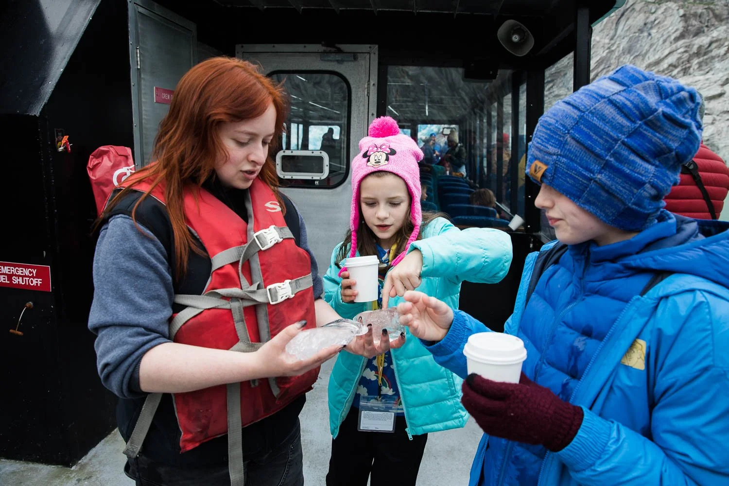 Excursion guide shows kids Alaska glacier ice.