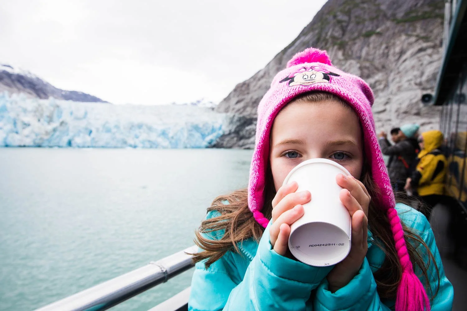 Girl drinks hot chocolate on a fjord in Alaska.