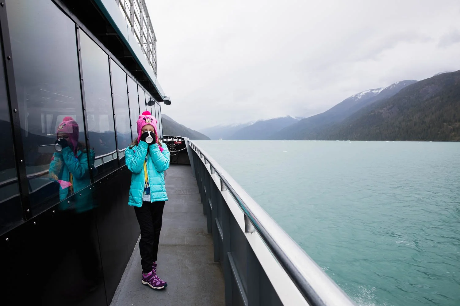 Girl sips on hot coca in a majestic Alaskan fjord.