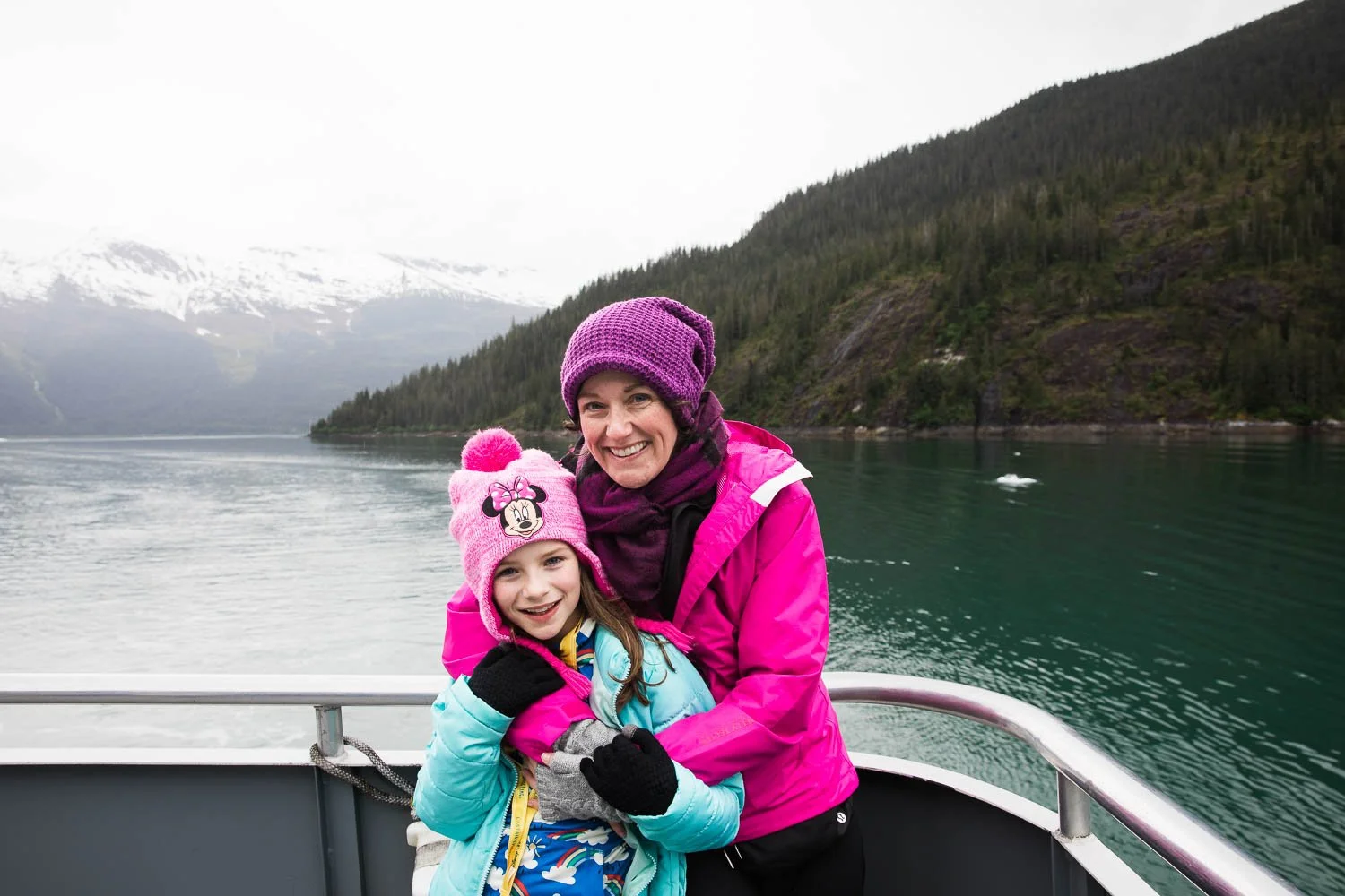 Mother and daughter pose on a boat in the Alaskan fjords.