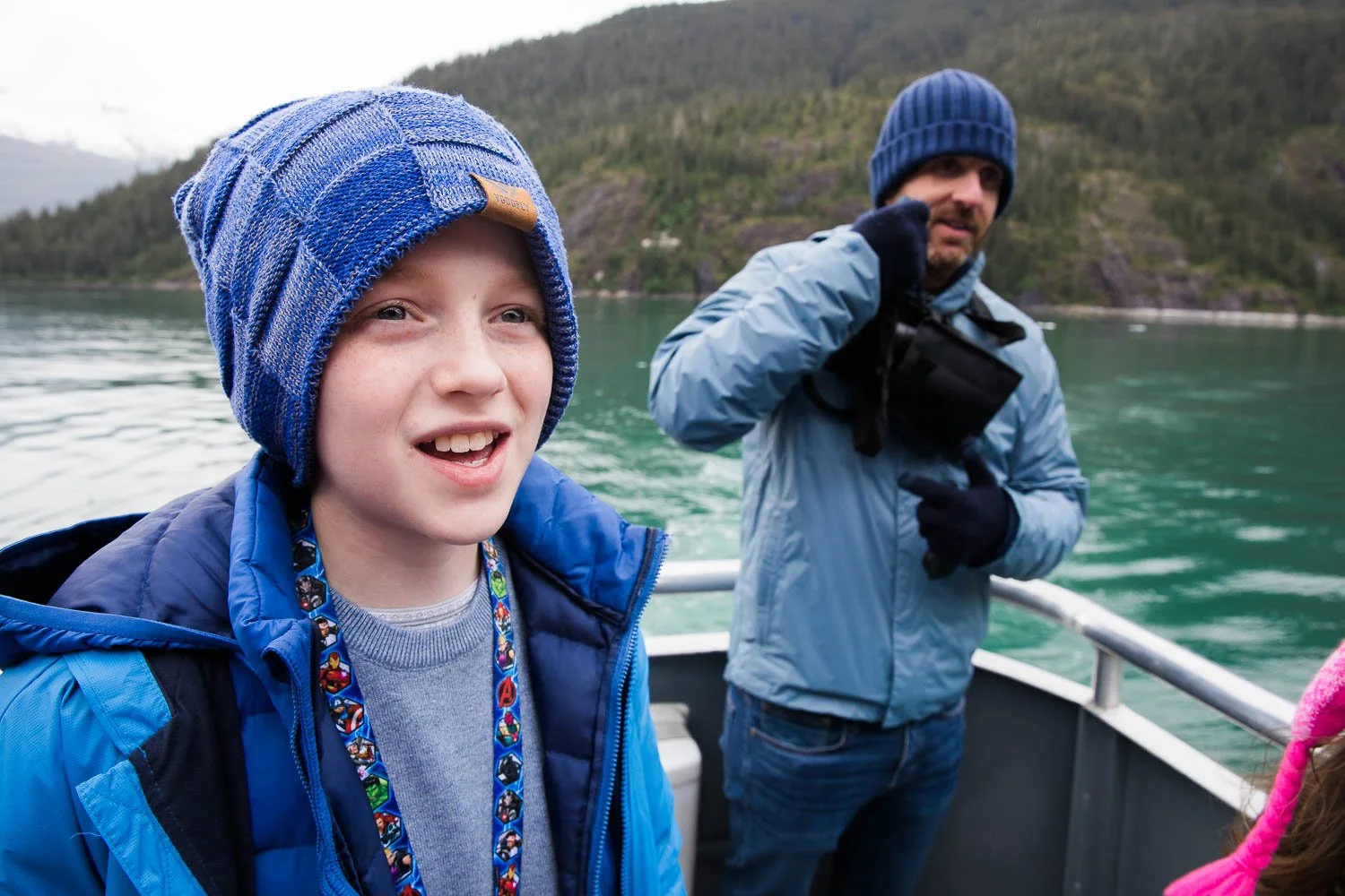Boy looks off at waterfalls in Alaska wilderness.