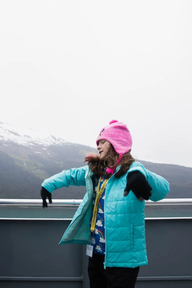 Tween girl dances on the back of a boat in Alaska.