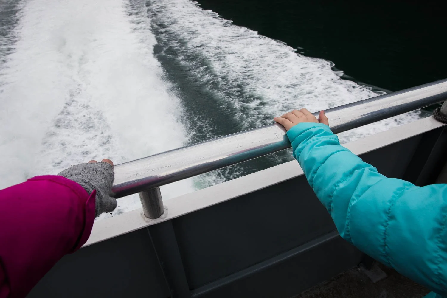 Holding the handrail as a boat moves through Alaskan fjord.